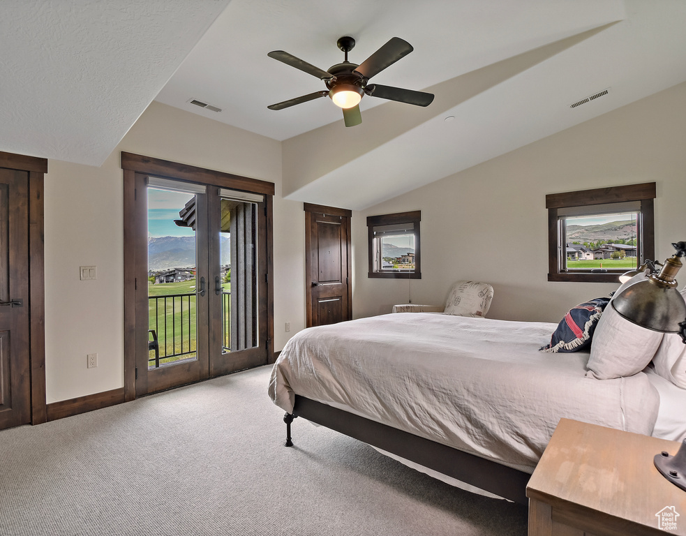 Bedroom with access to outside, carpet, multiple windows, a ceiling fan, and vaulted ceiling