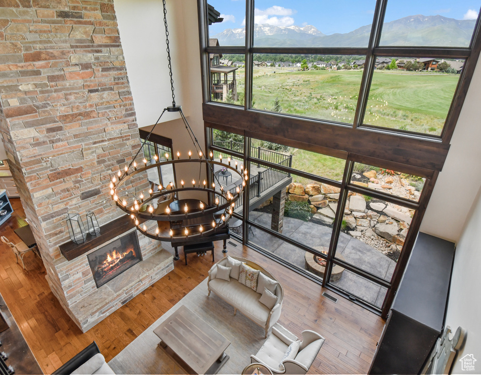 Interior space featuring a high ceiling, a glass covered fireplace, a mountain view, a chandelier, and wood finished floors