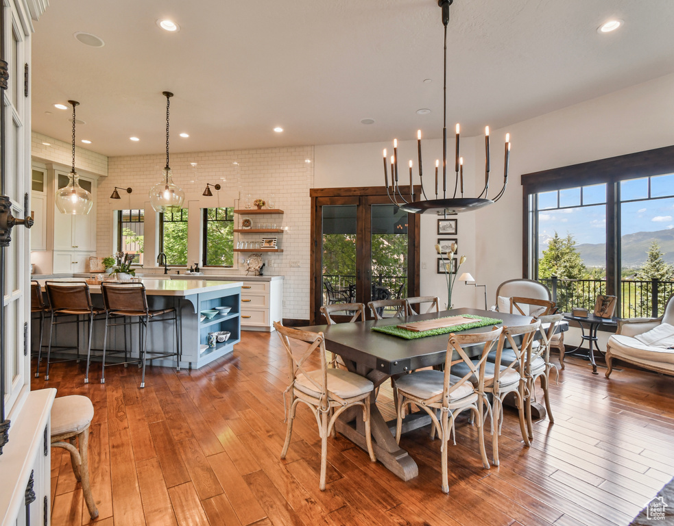 Dining space featuring light wood-style floors, healthy amount of natural light, recessed lighting, and brick wall