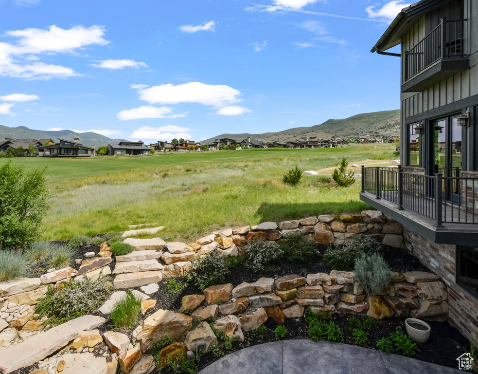 View of yard with a mountain view, a balcony, and a residential view