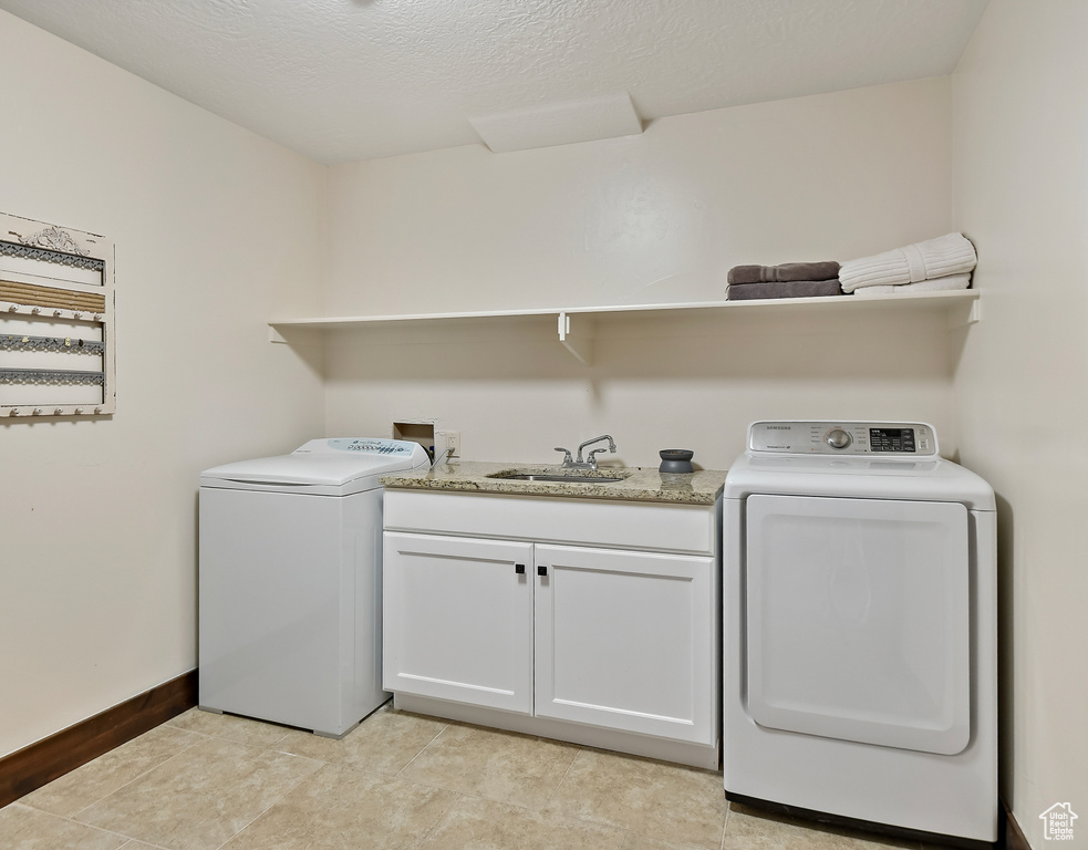 Washroom with cabinet space, baseboards, and independent washer and dryer