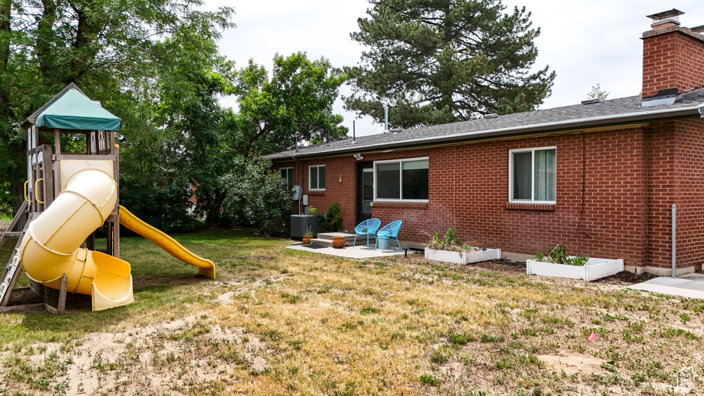 View of green lawn featuring a playground and central AC unit