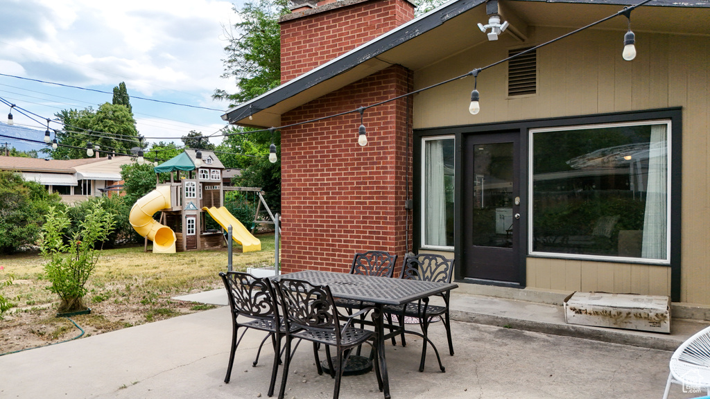 View of patio featuring a playground and outdoor dining area