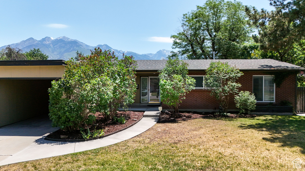 View of front of house featuring a front lawn, brick siding, a mountain view, and concrete driveway