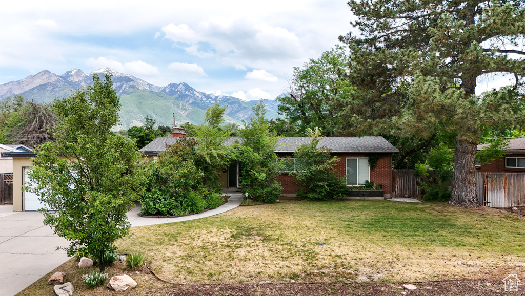 View of front of property featuring driveway, a mountain view, a garage, and brick siding