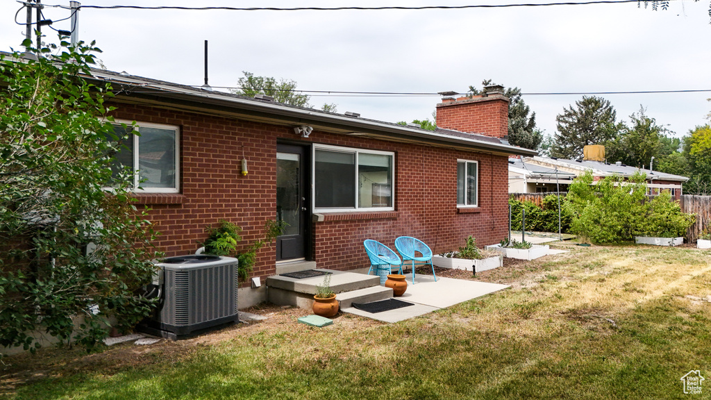Back of property with central AC unit, brick siding, and a chimney