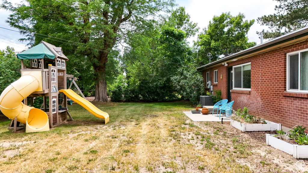 View of grassy yard with a playground and a garden
