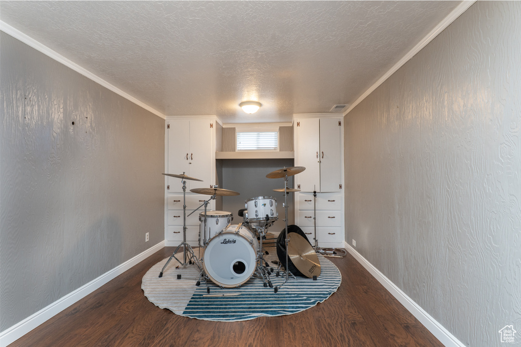 Recreation room with wood finished floors, a textured ceiling, baseboards, and ornamental molding
