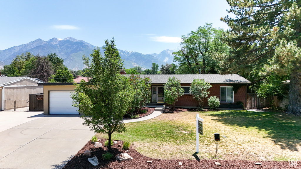 Ranch-style home with concrete driveway, a garage, a mountain view, and brick siding