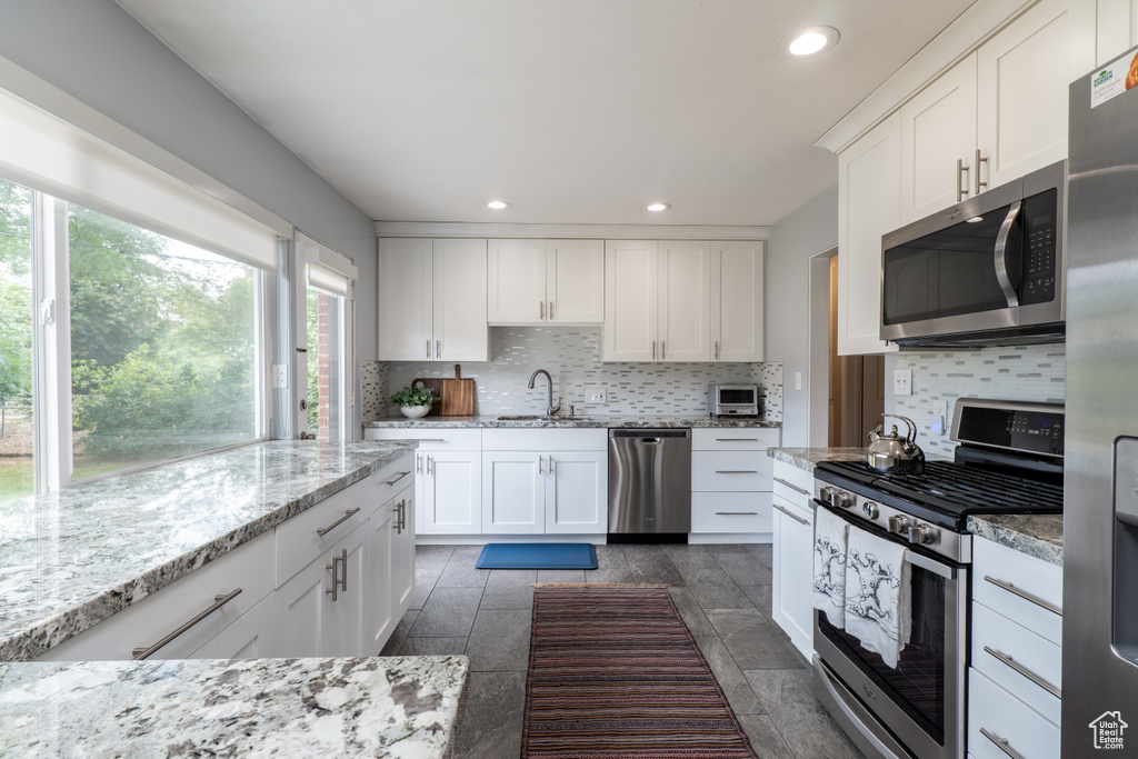 Kitchen featuring stainless steel appliances, a sink, tasteful backsplash, recessed lighting, and white cabinetry