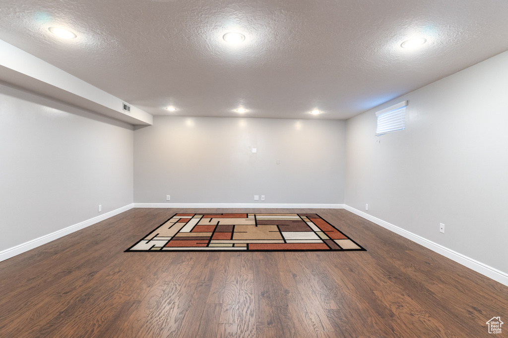 Below grade area featuring a textured ceiling, baseboards, wood finished floors, and recessed lighting