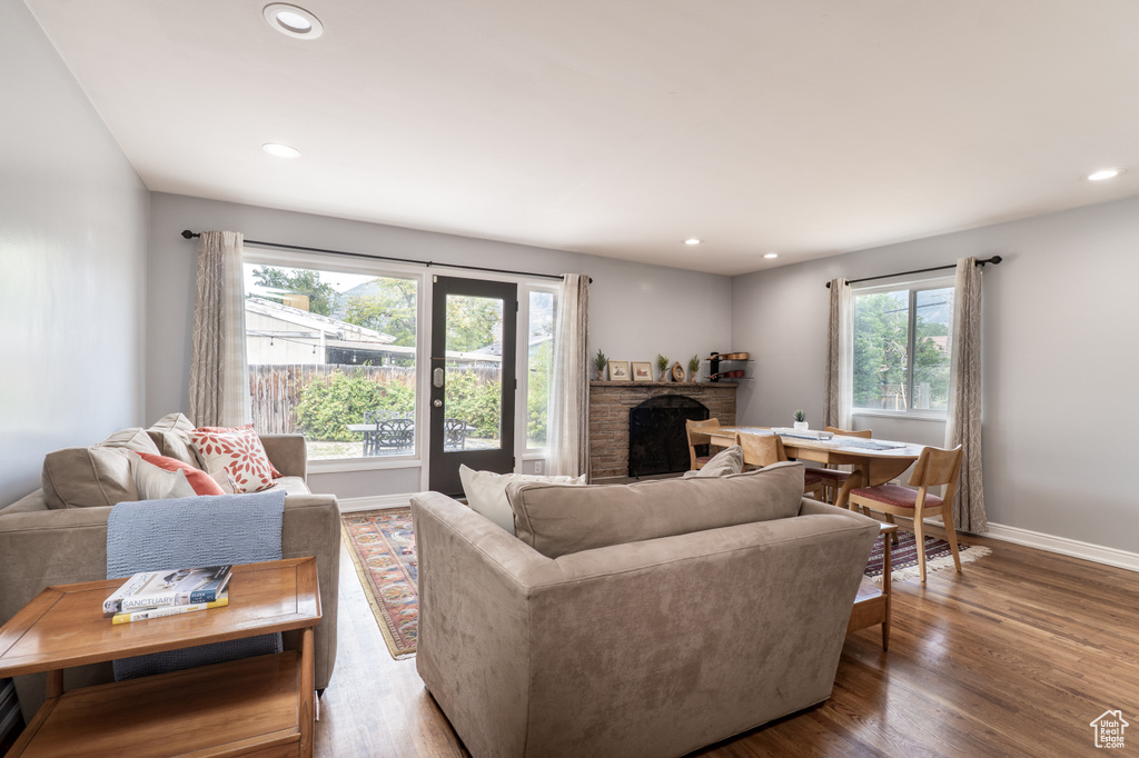 Living room featuring a fireplace, baseboards, wood finished floors, and recessed lighting