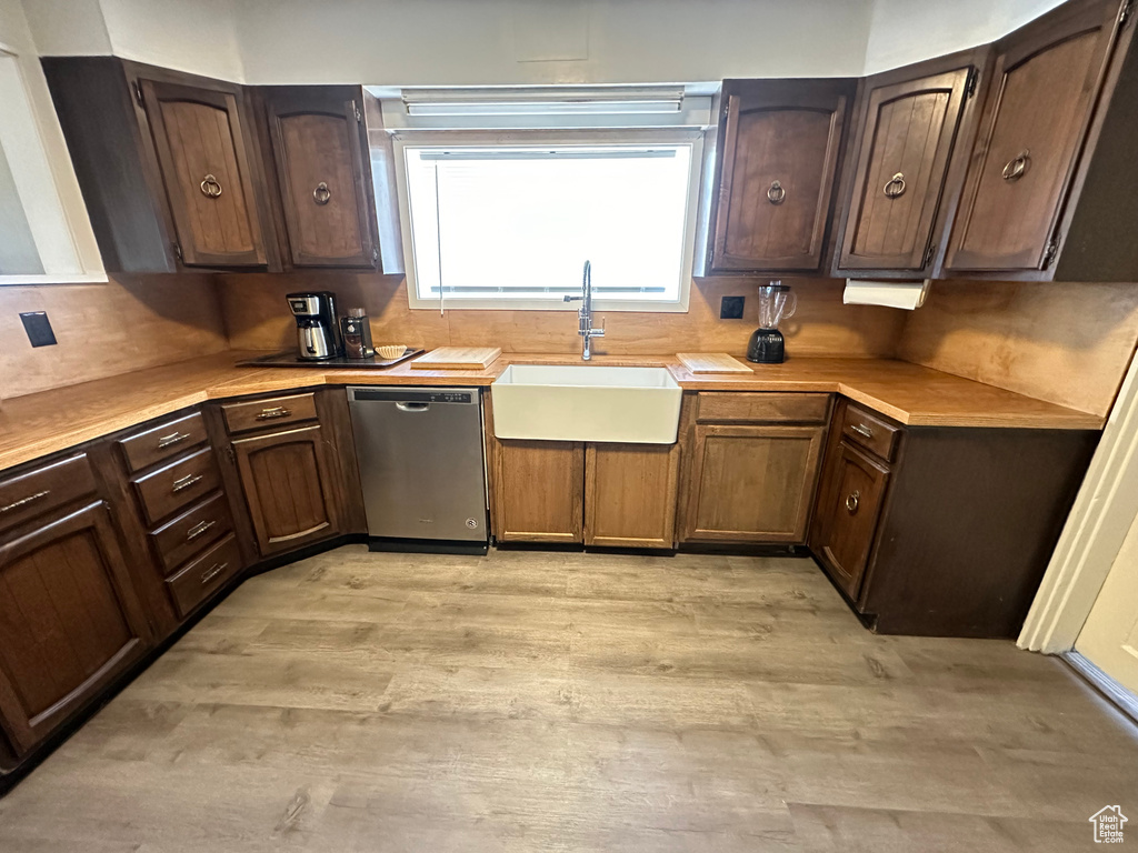 Kitchen featuring dishwasher, a sink, light wood-style floors, light countertops, and dark brown cabinetry