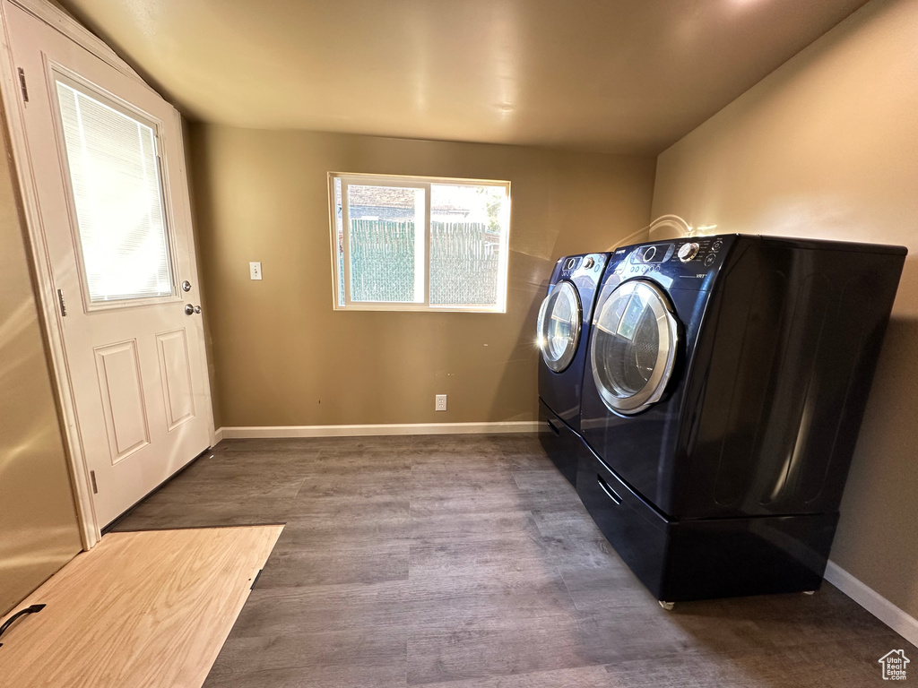 Washroom featuring washing machine and dryer, wood finished floors, and baseboards