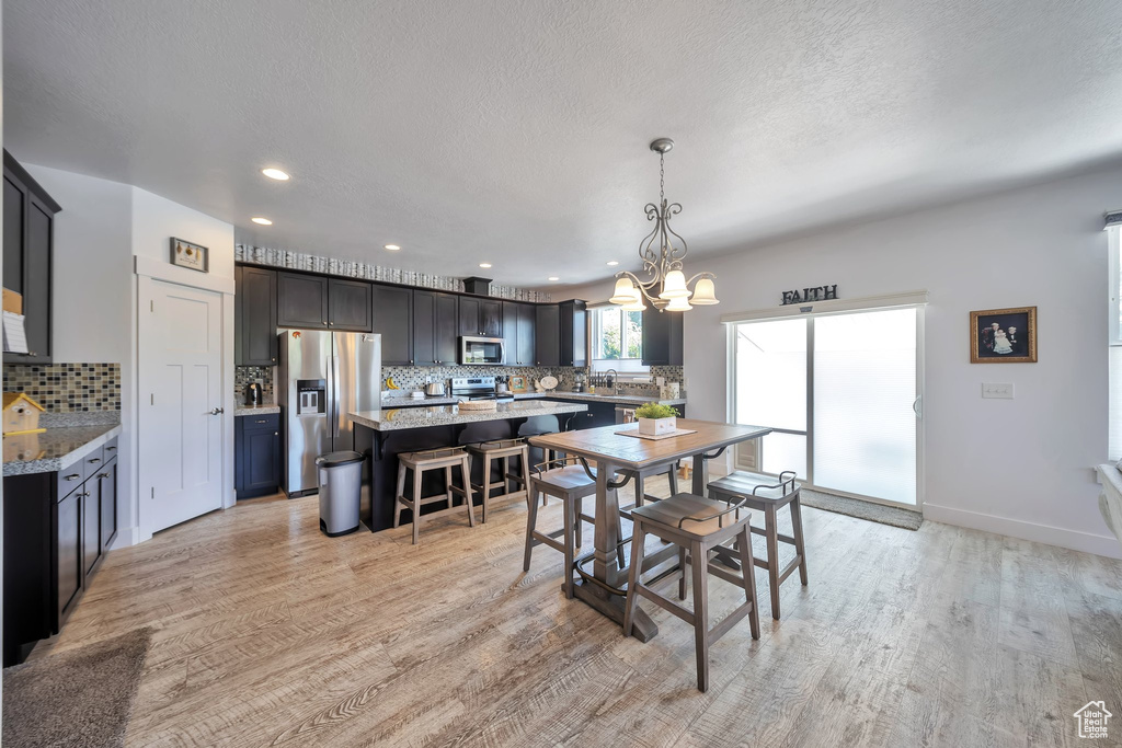 Dining space with a chandelier, light wood-type flooring, recessed lighting, and a textured ceiling