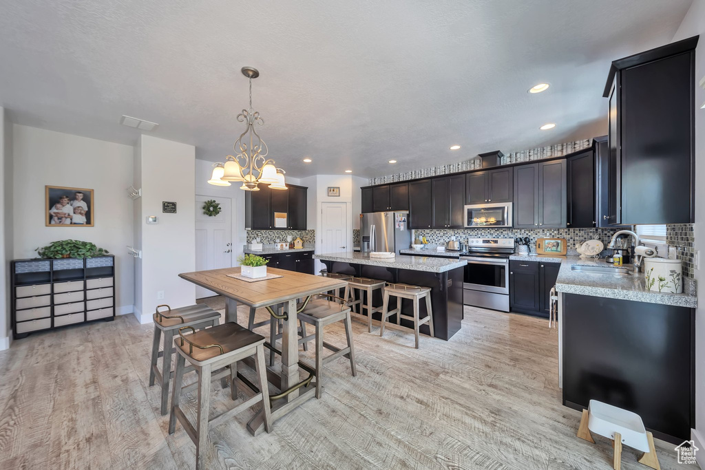 Dining area featuring a chandelier, light wood-style floors, and recessed lighting