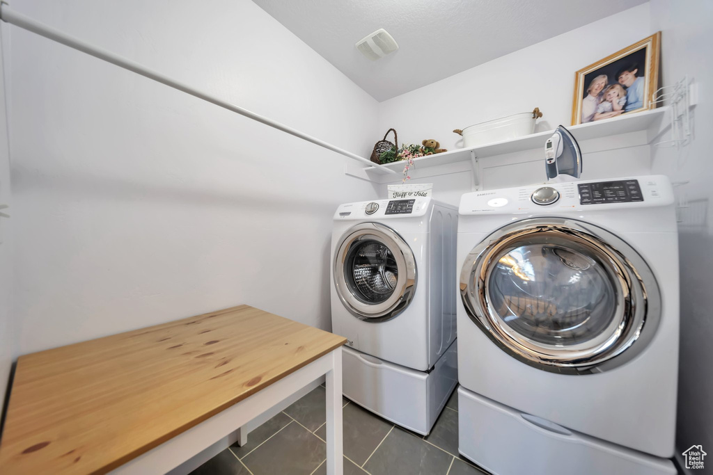 Laundry area featuring dark tile patterned floors and washing machine and dryer