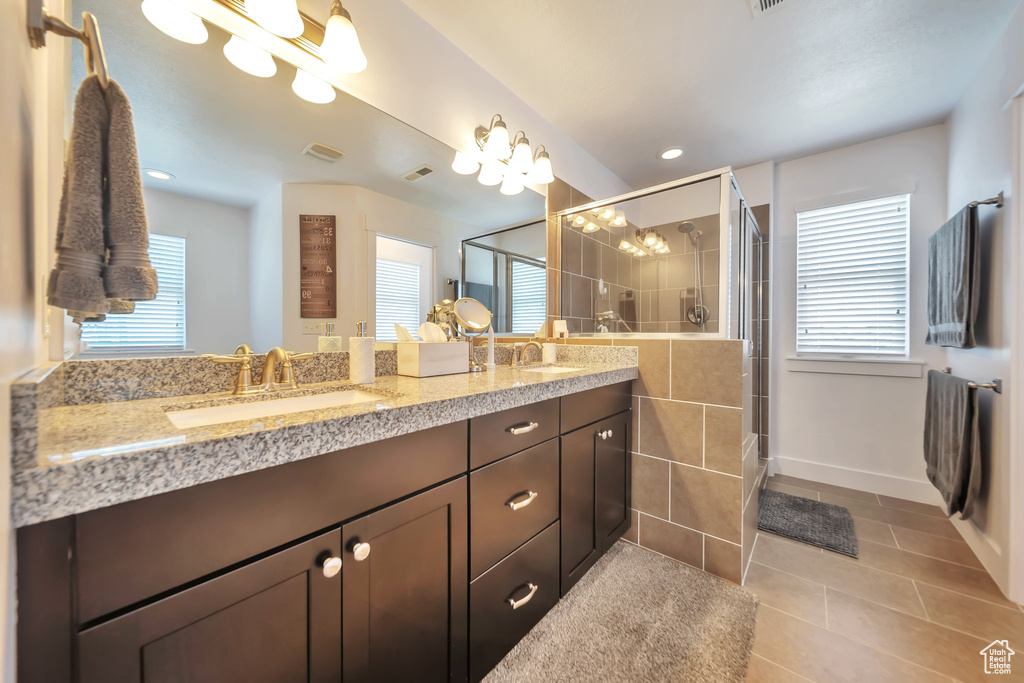 Bathroom featuring tile patterned floors, double vanity, a shower stall, and plenty of natural light