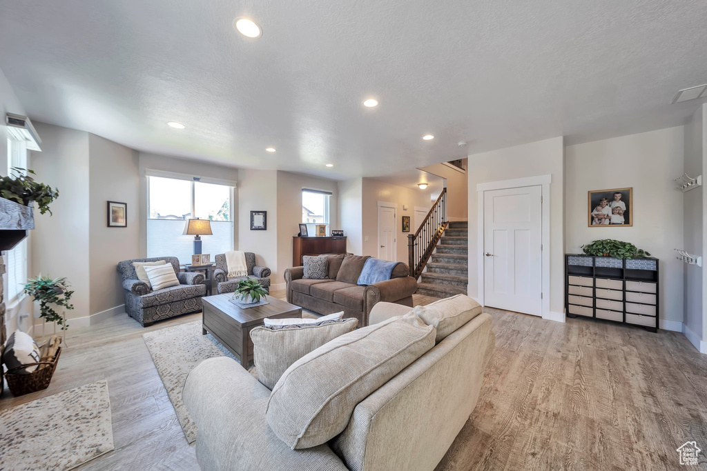 Living room featuring light wood finished floors, recessed lighting, stairway, and a textured ceiling