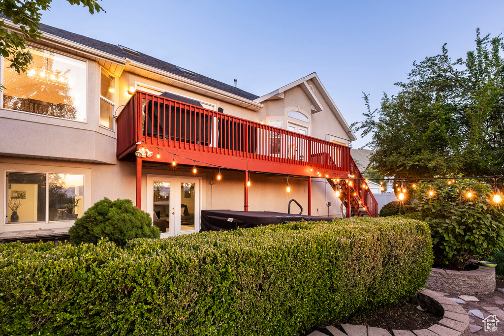 Back of property with french doors, stucco siding, a hot tub, and a wooden deck