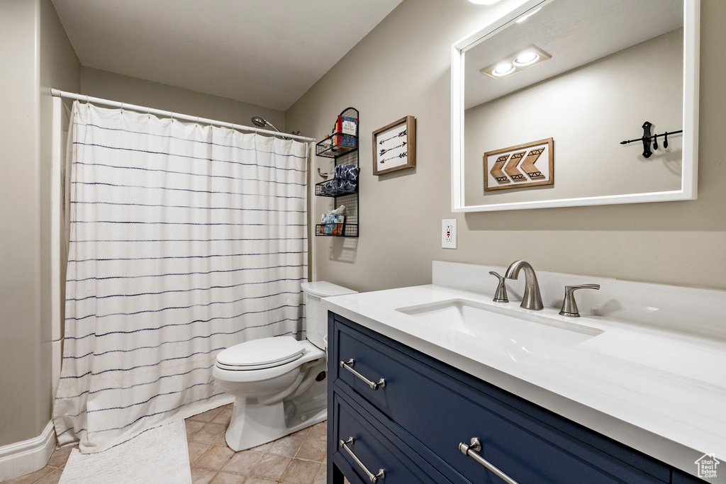 Full bathroom with vanity, toilet, curtained shower, and tile patterned floors