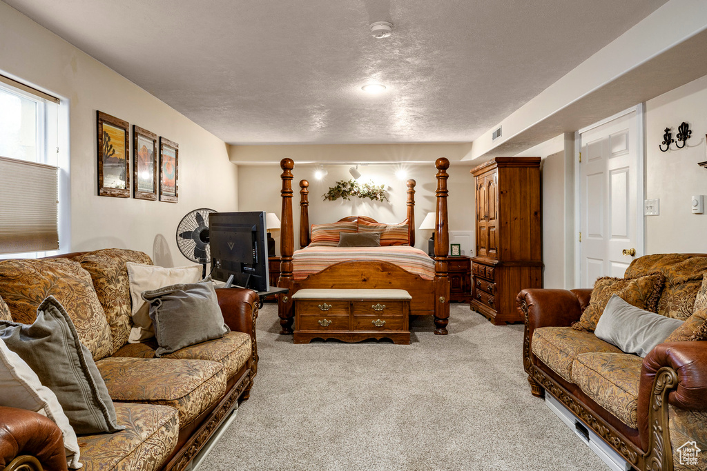Bedroom with light colored carpet and a textured ceiling