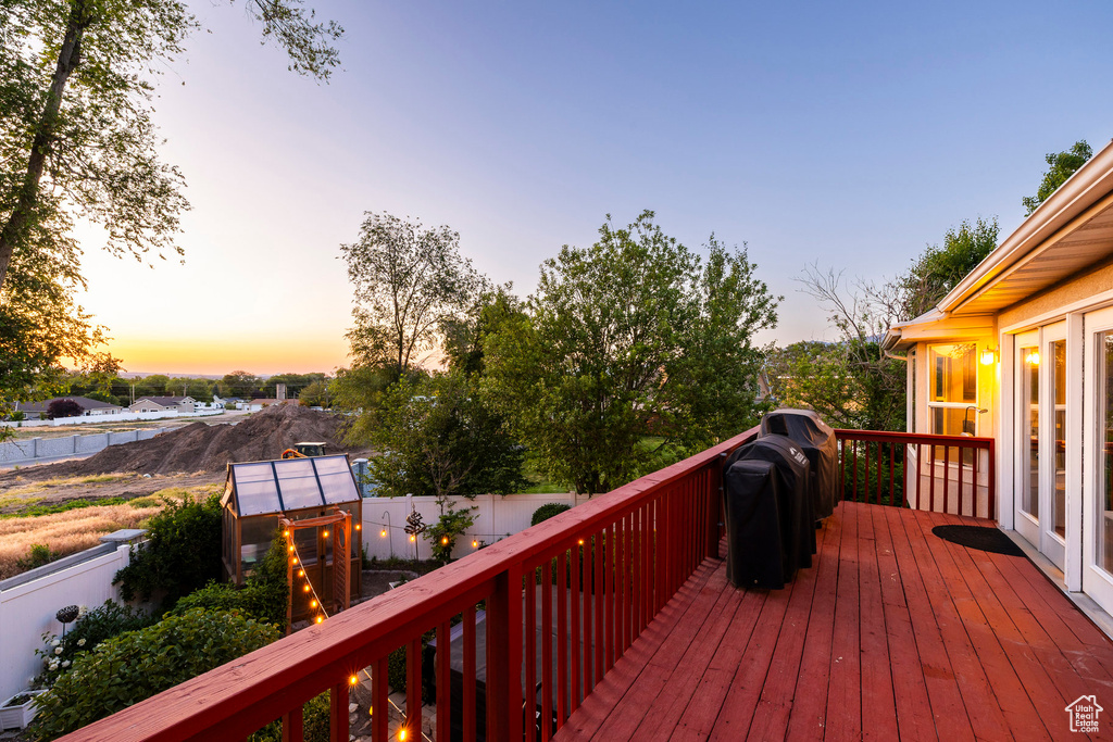 Deck at dusk with area for grilling and a fenced backyard
