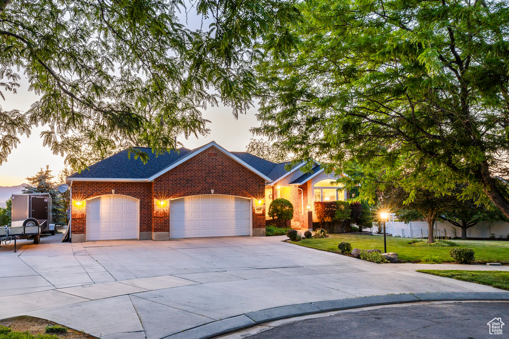 View of front of house with brick siding, concrete driveway, an attached garage, a front yard, and a shingled roof