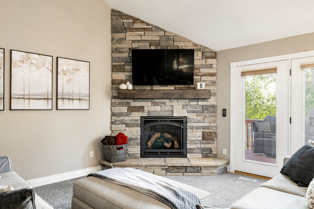Carpeted living room featuring vaulted ceiling, a fireplace, and baseboards