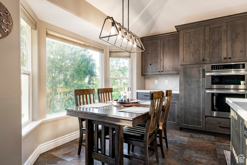 Dining area with stone tile flooring, baseboards, and lofted ceiling