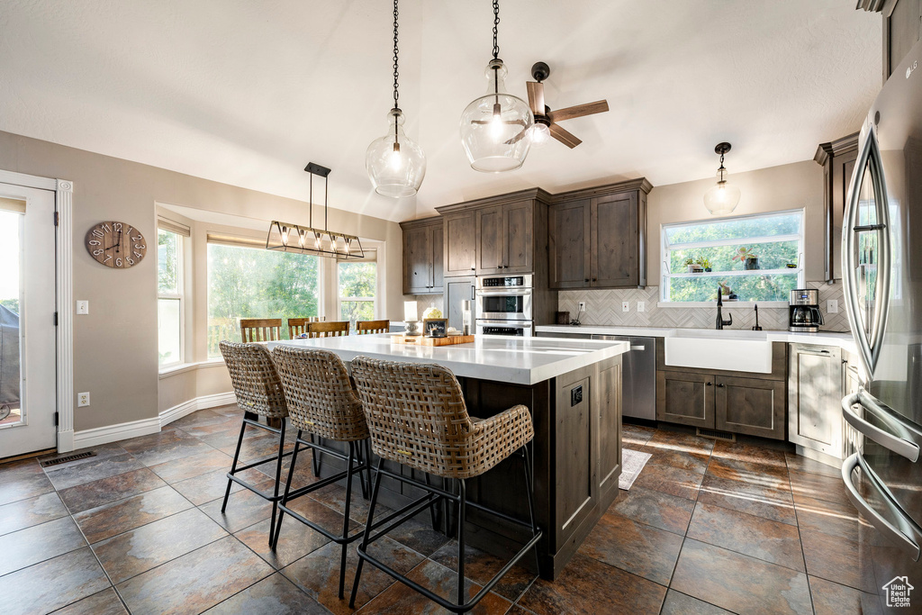 Kitchen featuring a sink, appliances with stainless steel finishes, healthy amount of natural light, stone tile floors, and vaulted ceiling