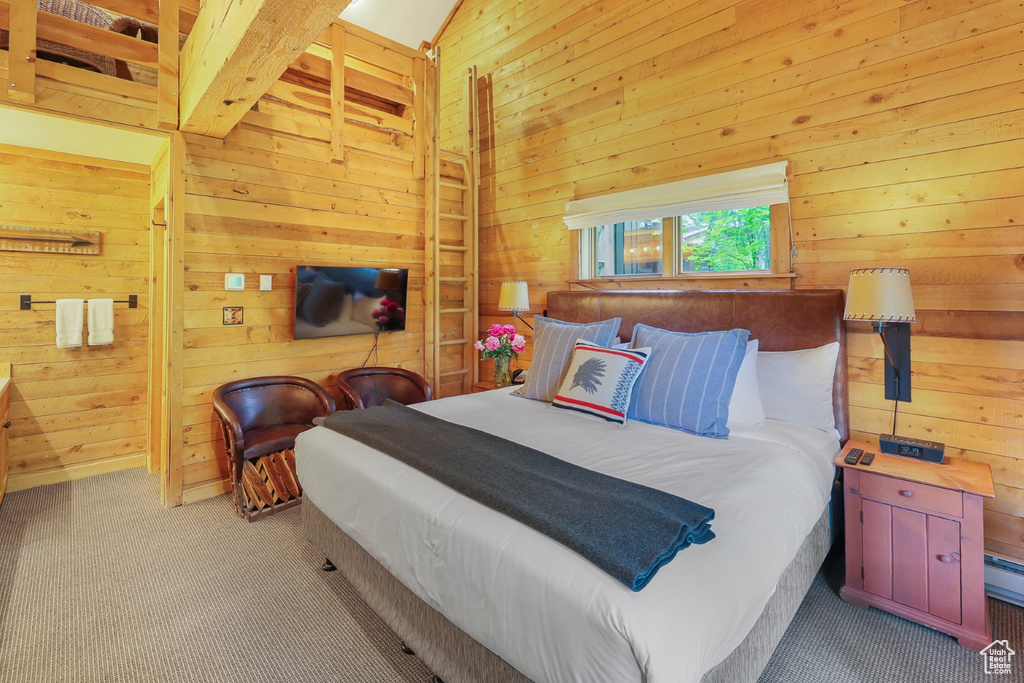 Bedroom featuring wood walls, carpet, beam ceiling, and baseboard heating