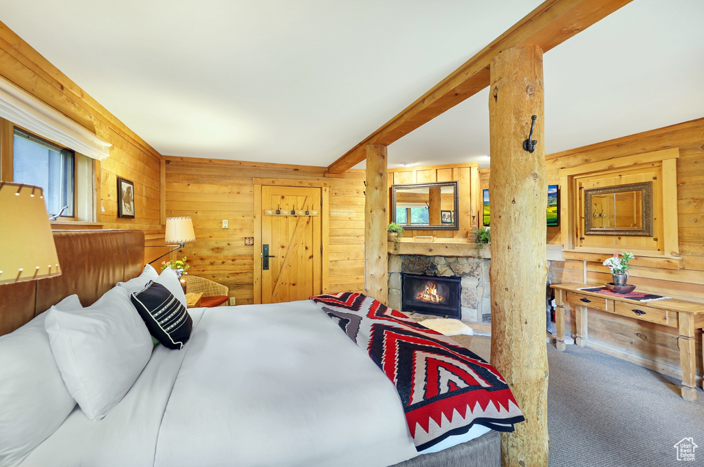 Bedroom featuring wooden walls, carpet flooring, and a fireplace