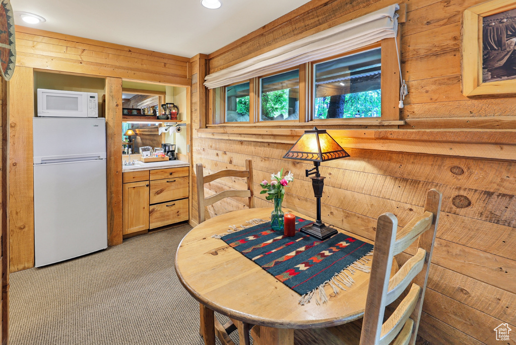 Carpeted dining space featuring wood walls and recessed lighting