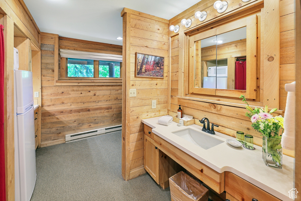 Bathroom with a baseboard heating unit, wood walls, and vanity