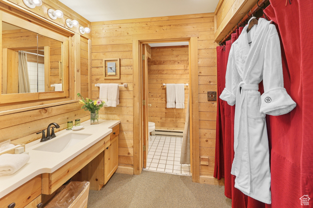 Full bathroom with toilet, vanity, wooden walls, a shower with shower curtain, and baseboard heating