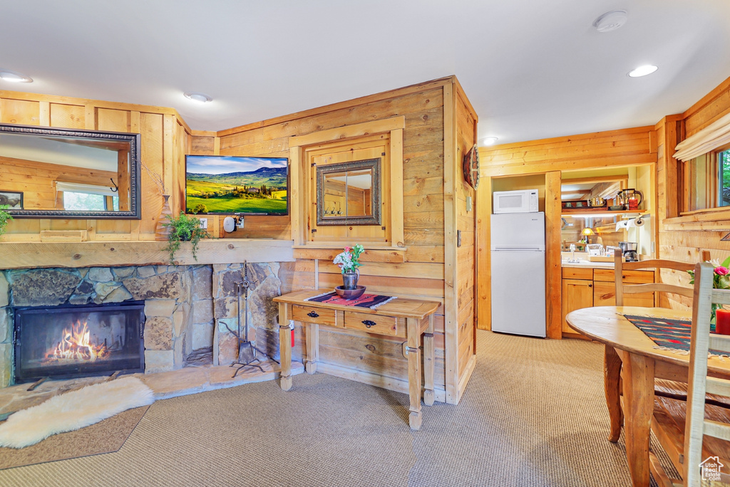 Interior space featuring wood walls, light colored carpet, a stone fireplace, and recessed lighting