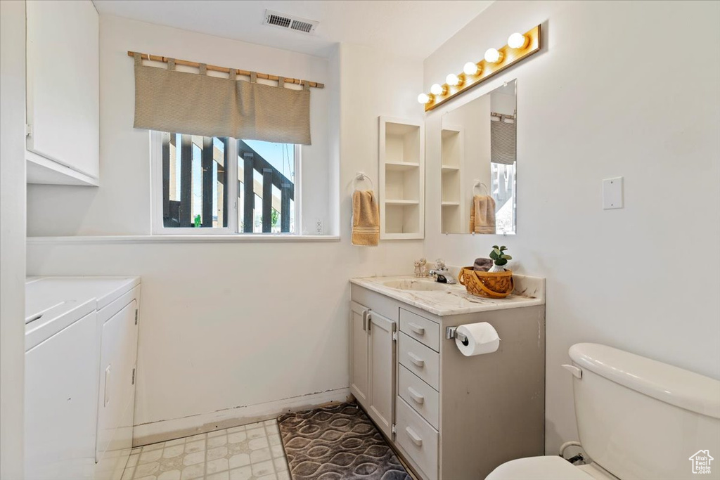 Full bath featuring washing machine and dryer, vanity, toilet, and tile patterned floors
