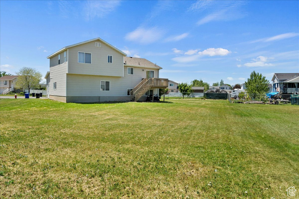 Rear view of property featuring stairway, a lawn, and a deck