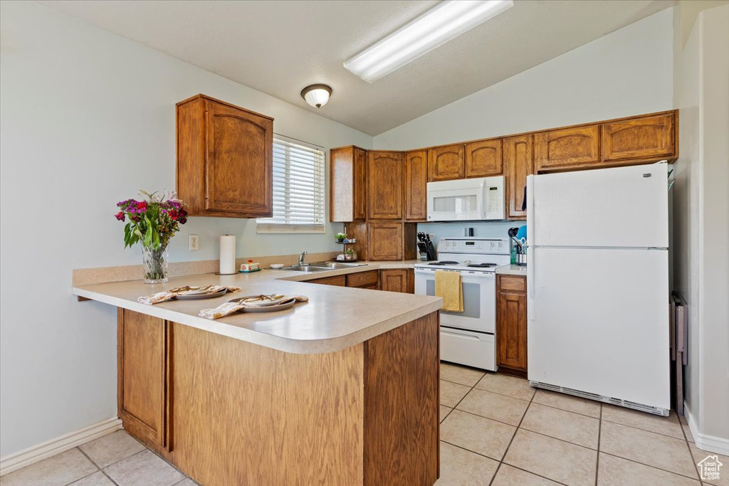 Kitchen featuring white appliances, a peninsula, lofted ceiling, light tile patterned floors, and light countertops