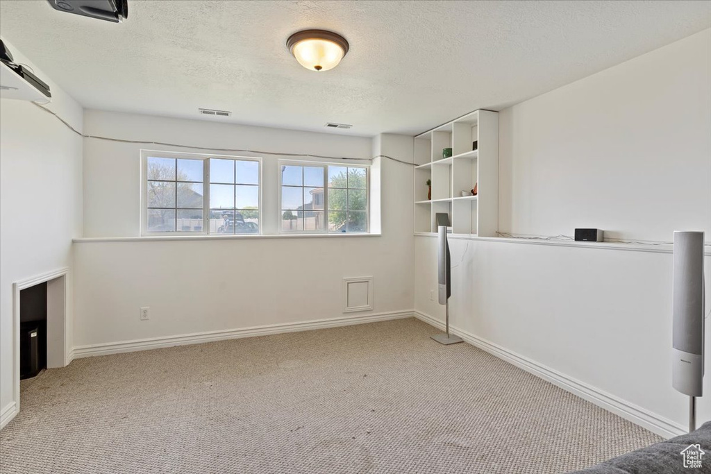 Interior space featuring carpet floors, a textured ceiling, and baseboards
