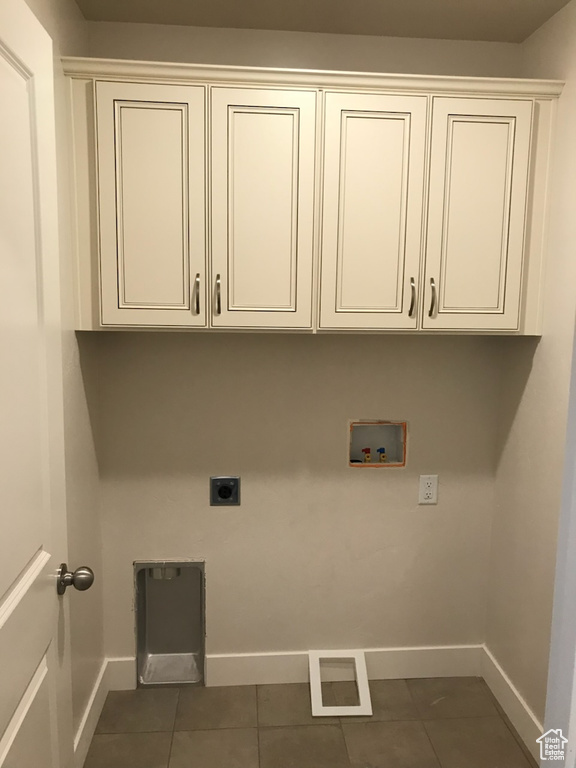 Laundry room featuring cabinet space, washer hookup, hookup for an electric dryer, baseboards, and dark tile patterned flooring