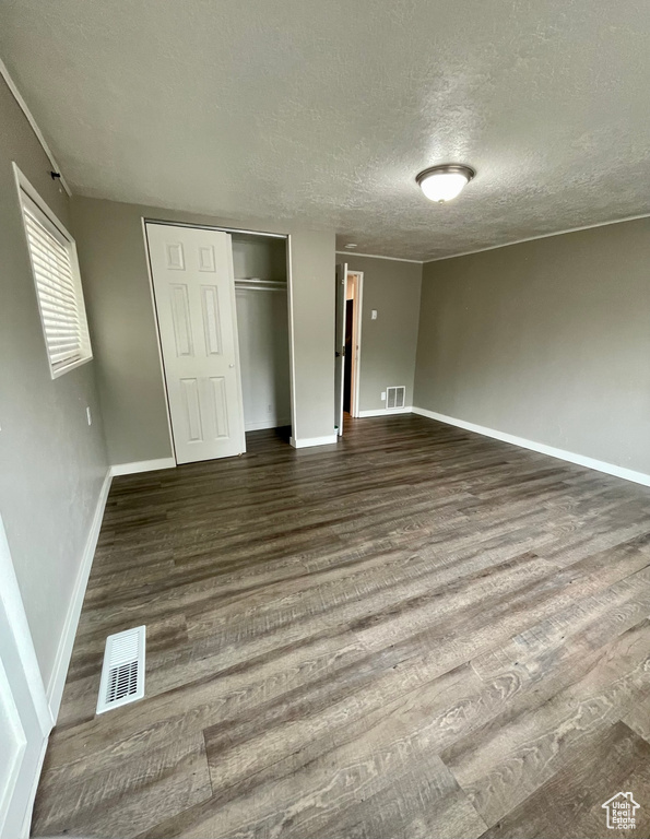 Unfurnished bedroom with wood finished floors, a textured ceiling, baseboards, and a closet
