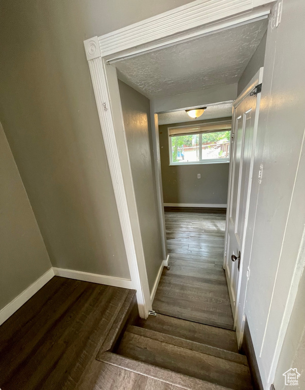 Stairs featuring wood finished floors, baseboards, and a textured ceiling