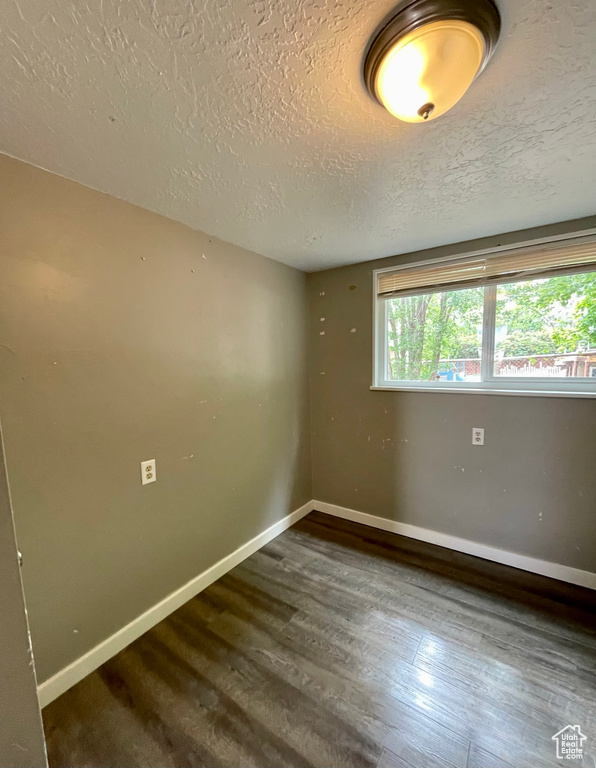 Empty room with healthy amount of natural light, a textured ceiling, wood finished floors, and baseboards
