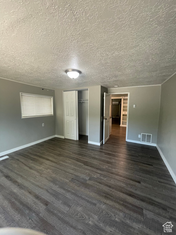Unfurnished bedroom with dark wood-type flooring, a textured ceiling, a closet, and baseboards