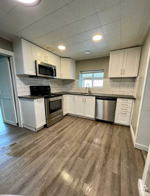 Kitchen with appliances with stainless steel finishes, dark countertops, a sink, and white cabinets