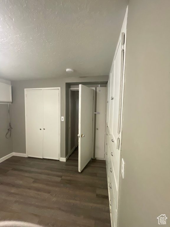 Unfurnished bedroom featuring dark wood-type flooring, a textured ceiling, and baseboards