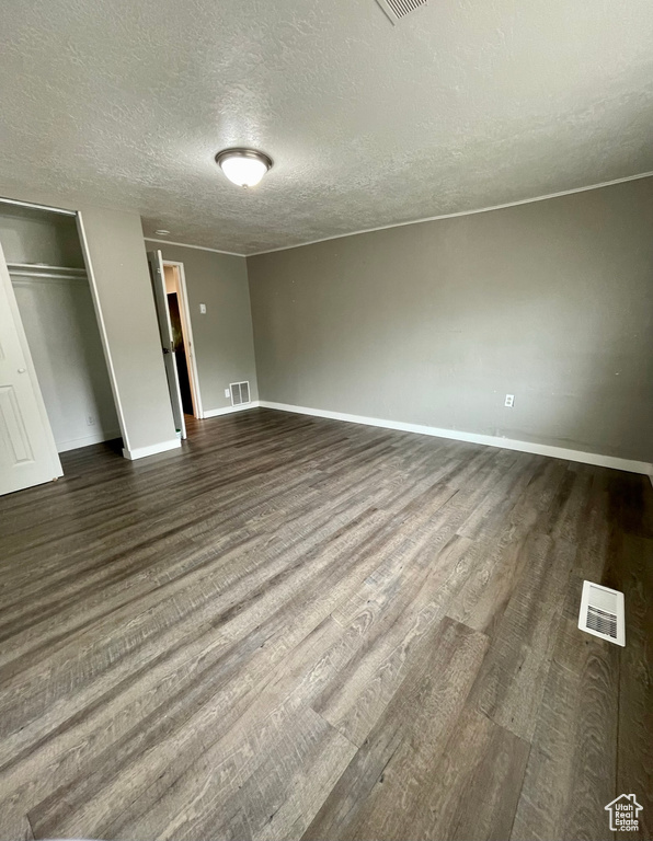 Unfurnished bedroom with dark wood-style floors, a textured ceiling, baseboards, and a closet
