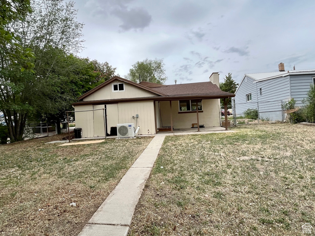 Back of house with a cooling unit, a yard, and a porch